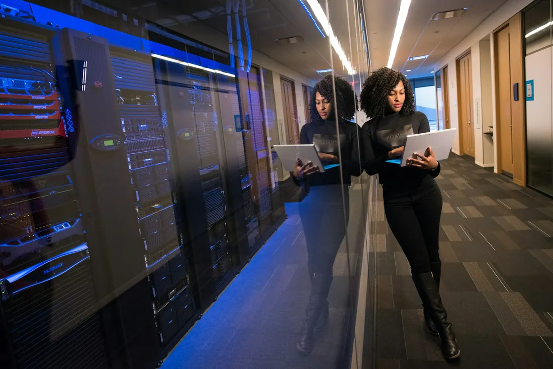 Two engineers in a server room with laptops