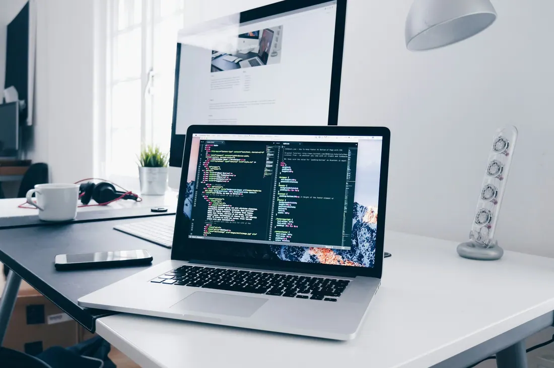 Code editor open on a laptop on a white desk